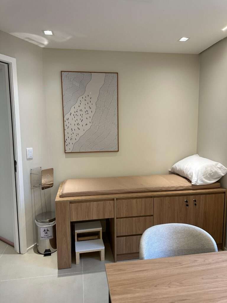 Sala de atendimento com maca de exame e mesa de consulta
