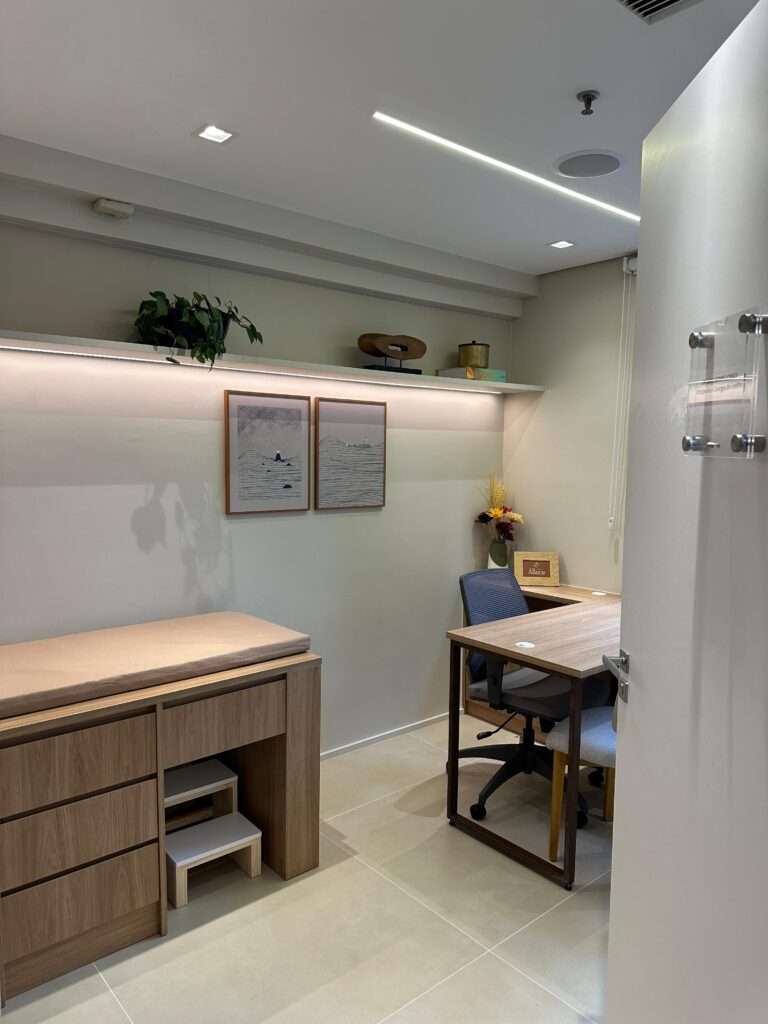 Sala de atendimento com mesa, cadeiras e pia para higienização